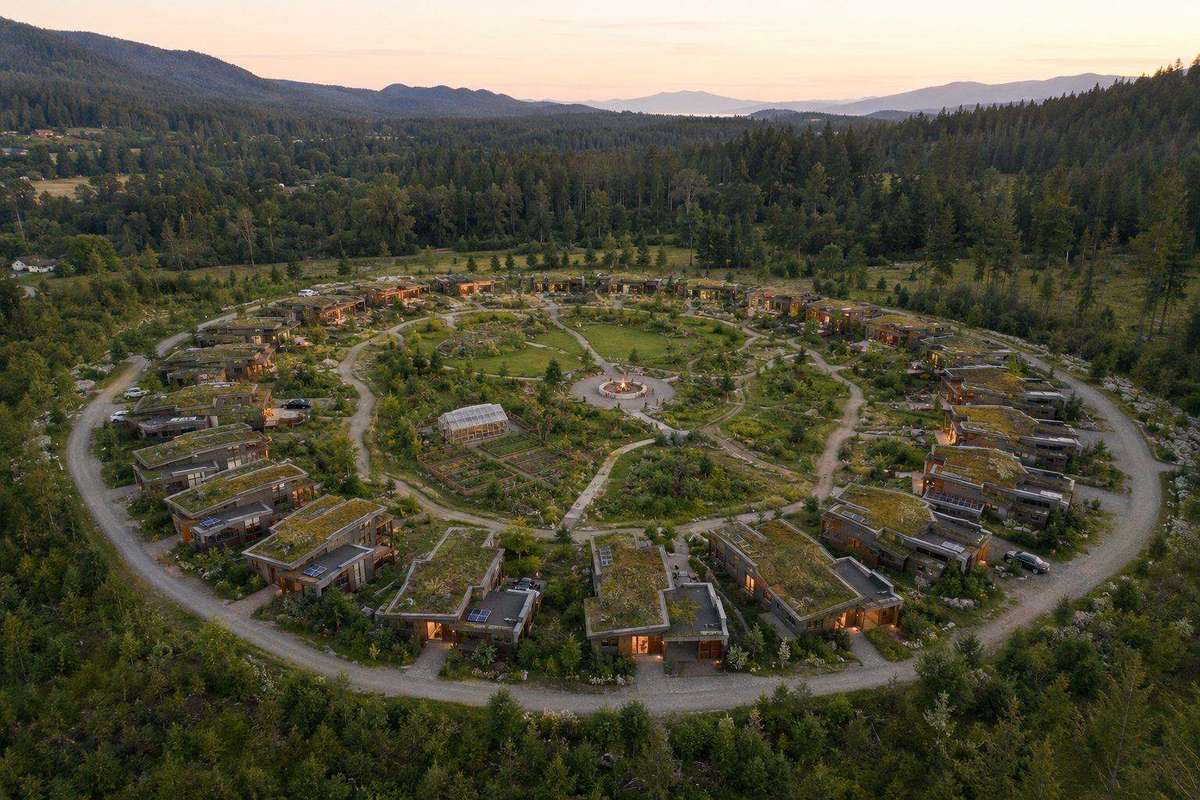 Conceptual rendering of Founder Village: a circle of homes around shared gardens and a central green, ringed by forest and mountains
